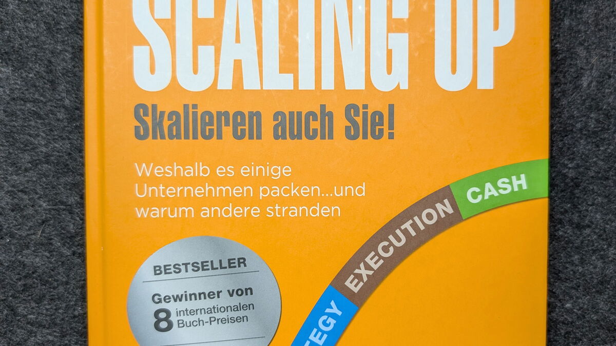 Buchcover von Scaling Up - Skalieren auch Sie!‘ von Verne Harnish, gelbes Hardcover mit farbiger People-Strategy-Execution-Cash-Grafik auf grauer Unterlage.